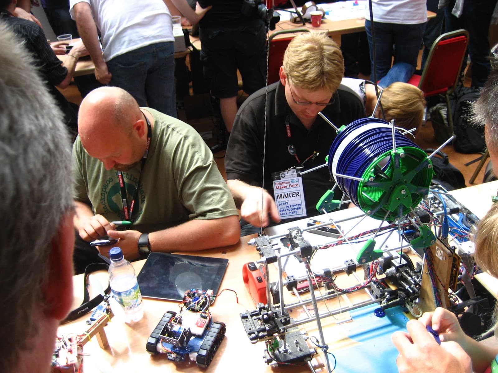 Makers demoing a small robot and 3D printer at a maker faire table